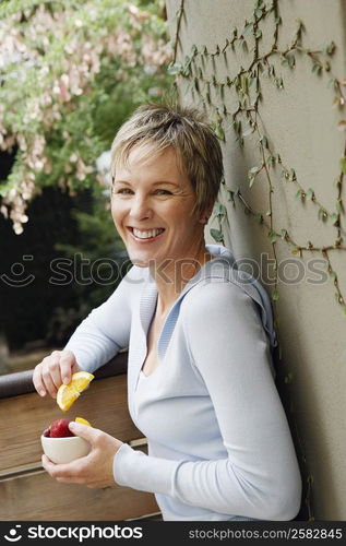 Portrait of a mature woman smiling and holding a bowl of fruit