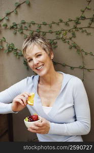 Portrait of a mature woman smiling and holding a bowl of fruit