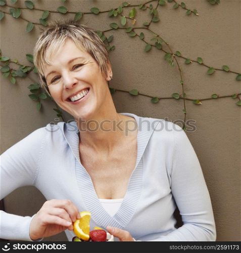 Portrait of a mature woman smiling and holding a bowl of fruit