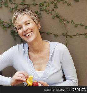 Portrait of a mature woman smiling and holding a bowl of fruit