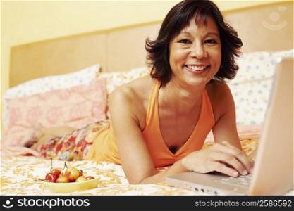 Portrait of a mature woman smiling and using a laptop