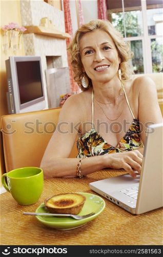 Portrait of a mature woman smiling in front of a laptop
