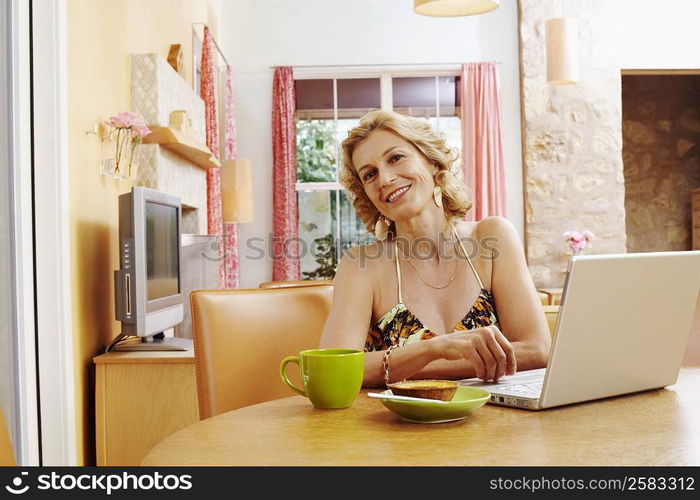 Portrait of a mature woman smiling in front of a laptop