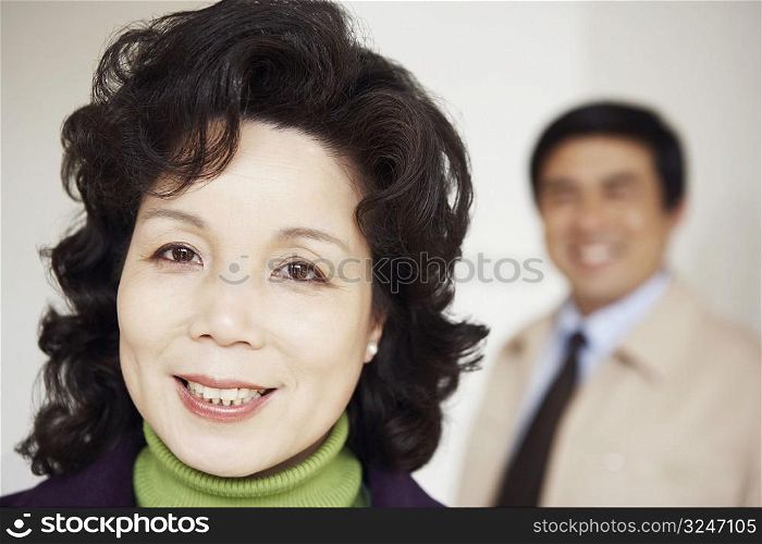Portrait of a mature woman smiling with a mature man behind her