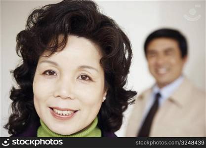 Portrait of a mature woman smiling with a mature man standing behind her