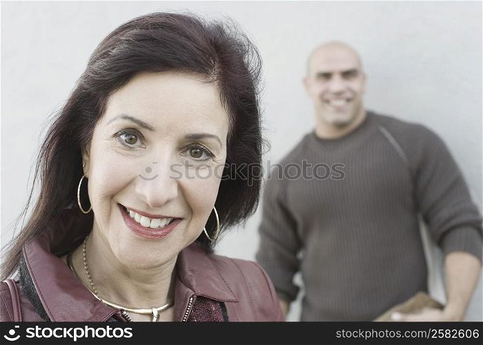 Portrait of a mature woman smiling with a mid adult man standing in the background