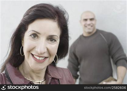 Portrait of a mature woman smiling with a mid adult man standing in the background