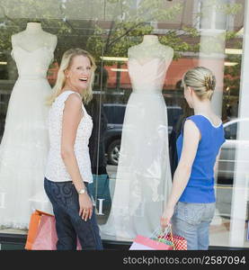 Portrait of a mature woman smiling with a mid adult woman looking at a mannequin in a window display