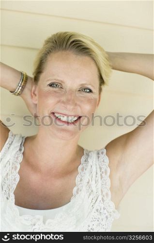 Portrait of a mature woman smiling with her hands behind her head
