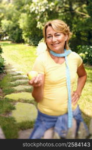 Portrait of a mature woman standing and holding a lemon