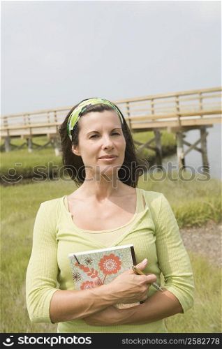 Portrait of a mature woman standing in a field and holding a book