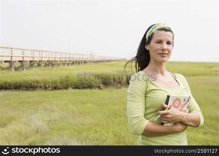 Portrait of a mature woman standing in a field and holding a book