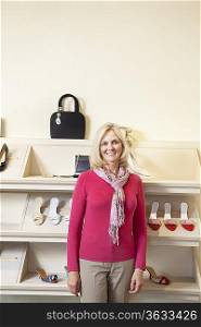 Portrait of a mature woman standing in front of footwear in shoe store