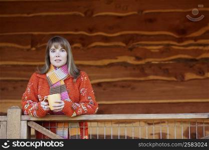 Portrait of a mature woman standing near a railing and holding a cup