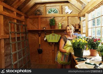 Portrait of a mature woman standing near potted plants