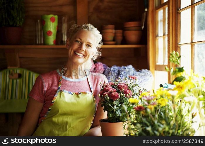 Portrait of a mature woman standing near potted plants