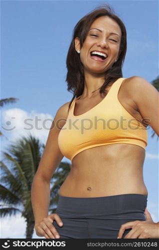 Portrait of a mature woman standing with arms akimbo and laughing