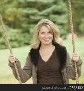 Portrait of a mature woman swinging on a rope swing