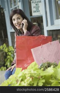 Portrait of a mature woman talking on a mobile phone in front of a store