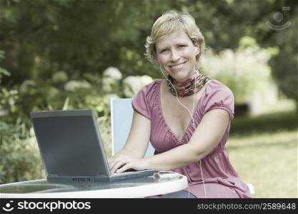 Portrait of a mature woman using a laptop and listening to an mp3 player