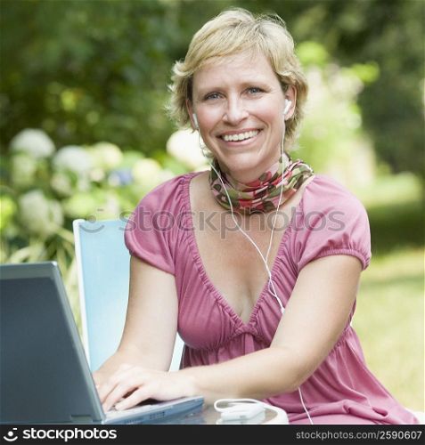 Portrait of a mature woman using a laptop and listening to an mp3 player