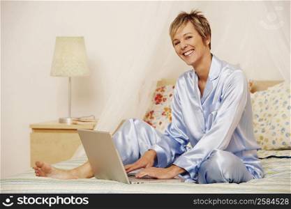 Portrait of a mature woman using a laptop on the bed and smiling
