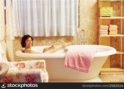 Portrait of a mature woman using a sponge in a bathtub and smiling