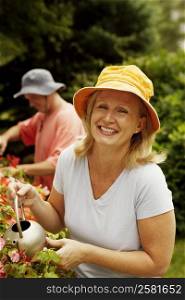 Portrait of a mature woman watering plants and smiling