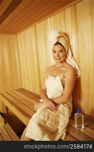 Portrait of a mature woman wearing towel sitting in a sauna