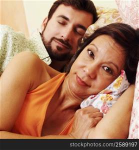 Portrait of a mature woman with a mature man sleeping behind her