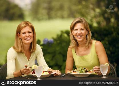 Portrait of a mature woman with a mid adult woman sitting at a table and smiling