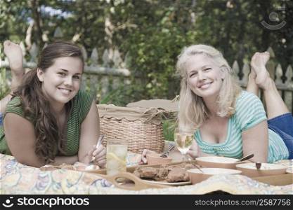 Portrait of a mature woman with her daughter having picnic in a park