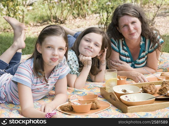 Portrait of a mature woman with her two daughters having picnic in a park