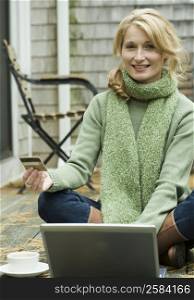Portrait of a mature woman working on a laptop and holding a credit card