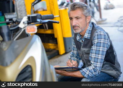 portrait of a mechanic assessing scooter