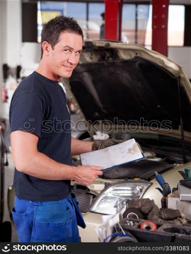 Portrait of a mechanic, looking at the camera with a service report in hand
