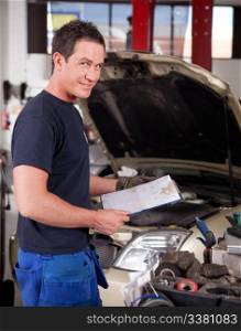 Portrait of a mechanic, looking at the camera with a service report in hand