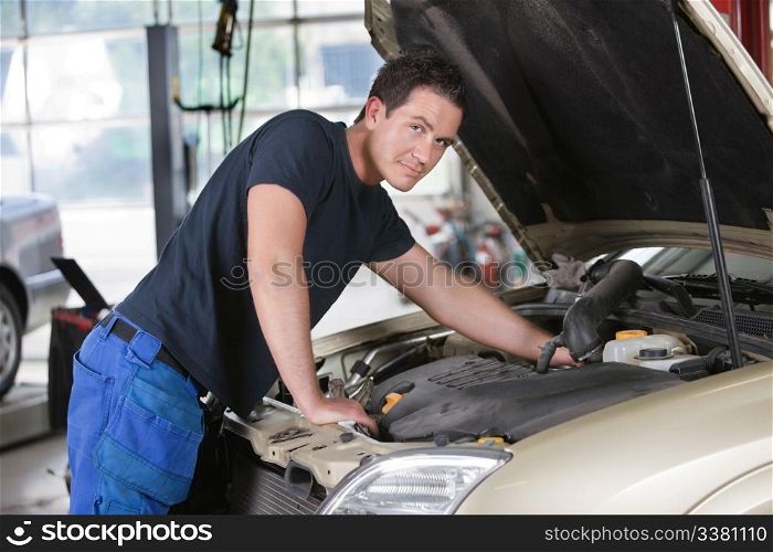 Portrait of a mechanic working on car in garage
