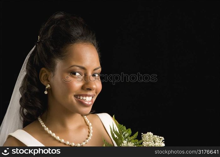 Portrait of a mid-adult African-American bride on black background.
