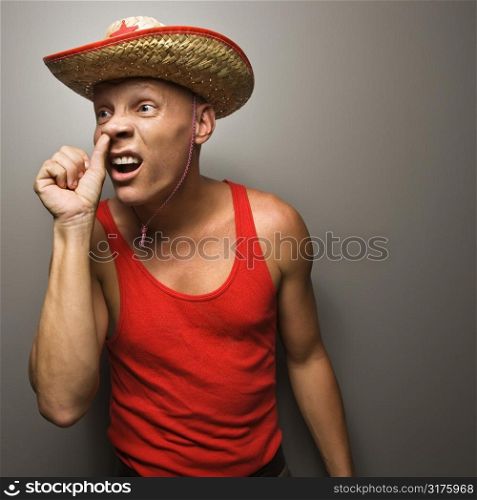 Portrait of a Mid-adult Caucasian male wearing straw hat with thumb up his nos.