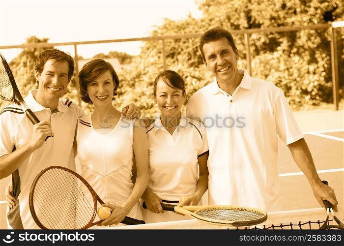 Portrait of a mid adult couple and a mature couple standing together on a tennis court