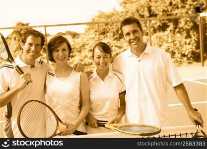 Portrait of a mid adult couple and a mature couple standing together on a tennis court