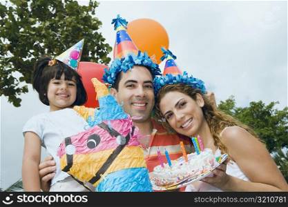Portrait of a mid adult couple celebrating birthday with their daughter