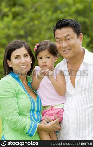 Portrait of a mid adult couple posing with their daughter and smiling