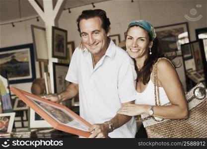 Portrait of a mid adult couple purchasing paintings from a store