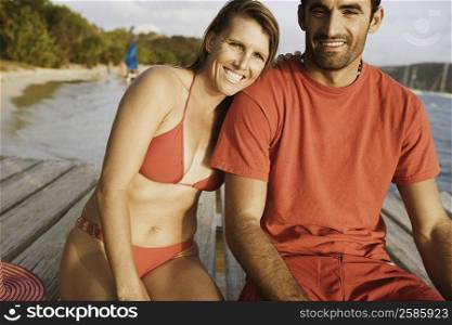 Portrait of a mid adult couple sitting on a pier and smiling