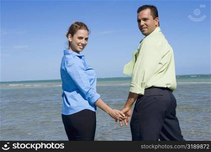 Portrait of a mid adult couple standing on the beach with holding their hands
