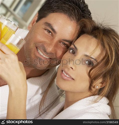 Portrait of a mid adult couple toasting with glasses of juice