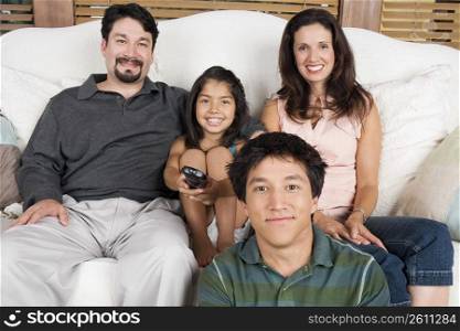 Portrait of a mid adult couple watching television with their son and daughter