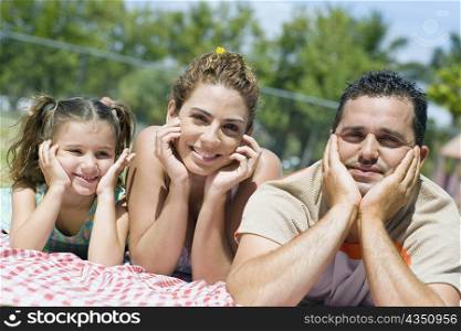 Portrait of a mid adult couple with their daughter lying on a picnic blanket
